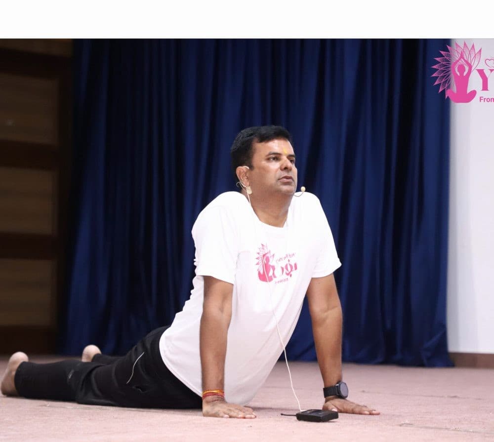 Manish Jain demonstrating cobra pose on stage