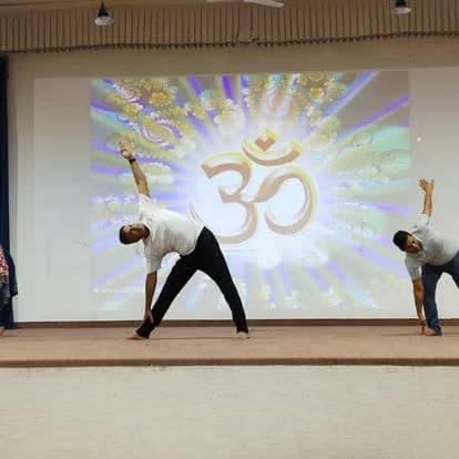 A stage yoga demonstration in front of an Om backdrop